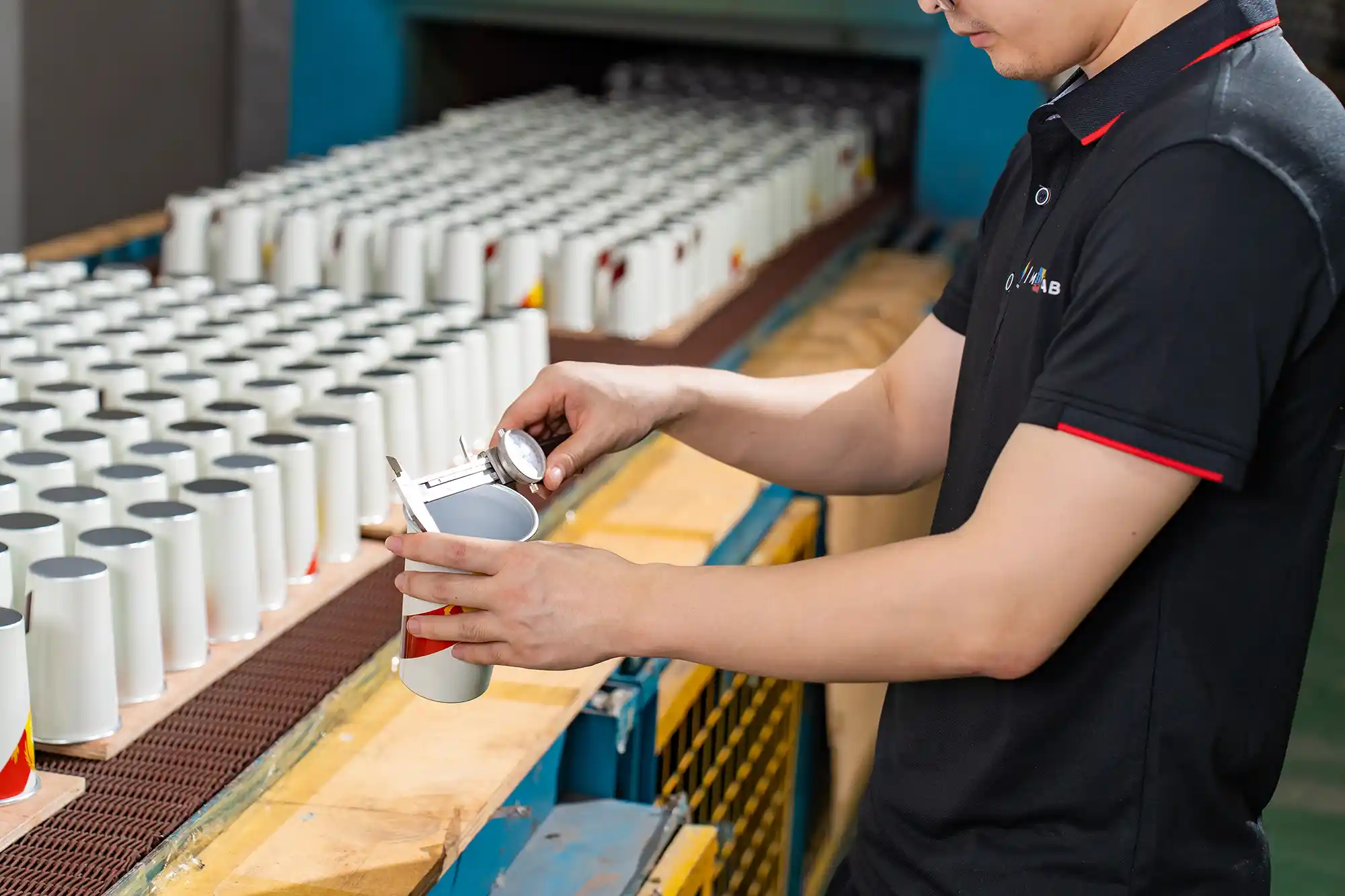 Quality engineer performing precision digital caliper measurement on tumbler lid thread
